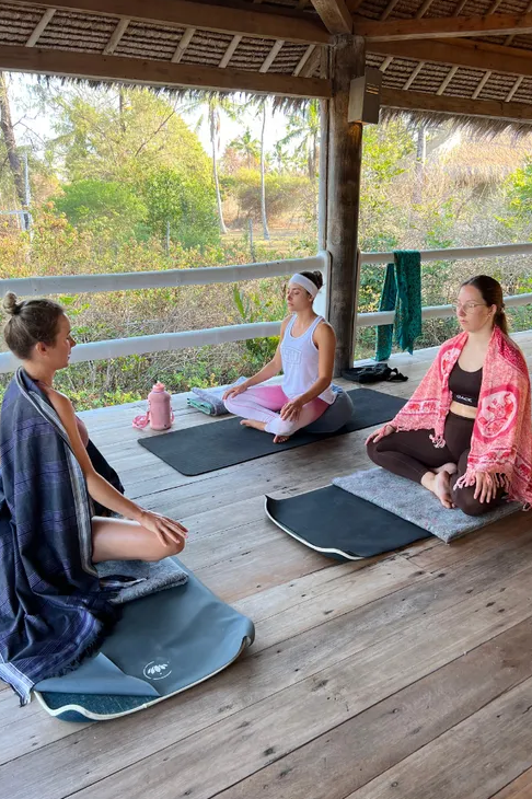 Three people meditate on yoga mats.