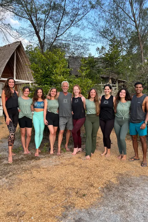 A group of people standing and smiling for the camera in a tropical place.